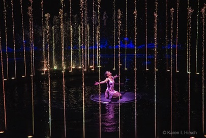 Woman lead crouched in the middle of a circle of water sprays